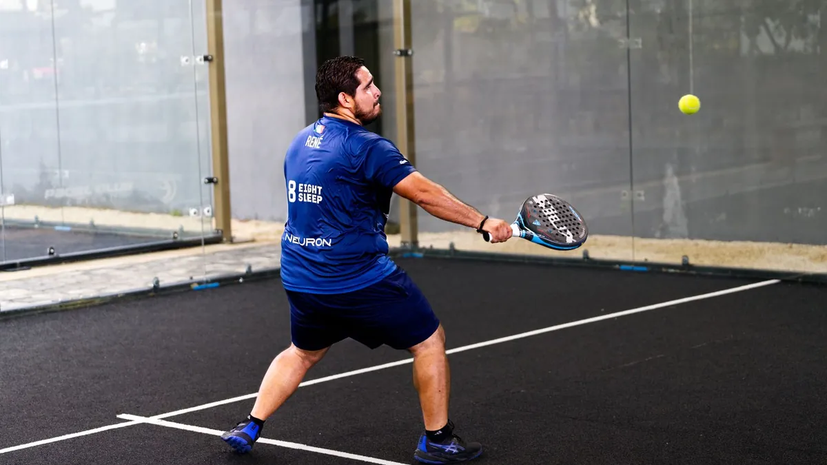 Man engaged in padel action in Mérida, showcasing skill on an indoor court.