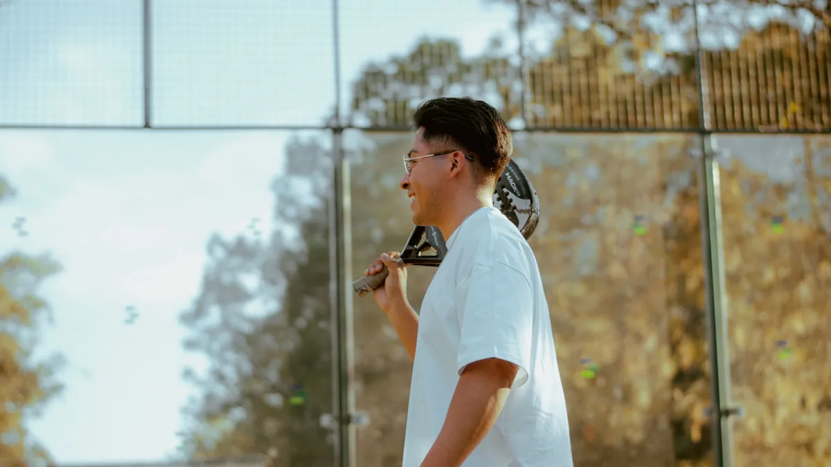 A young man with a paddle racket standing outdoors, exuding confidence and sports spirit.